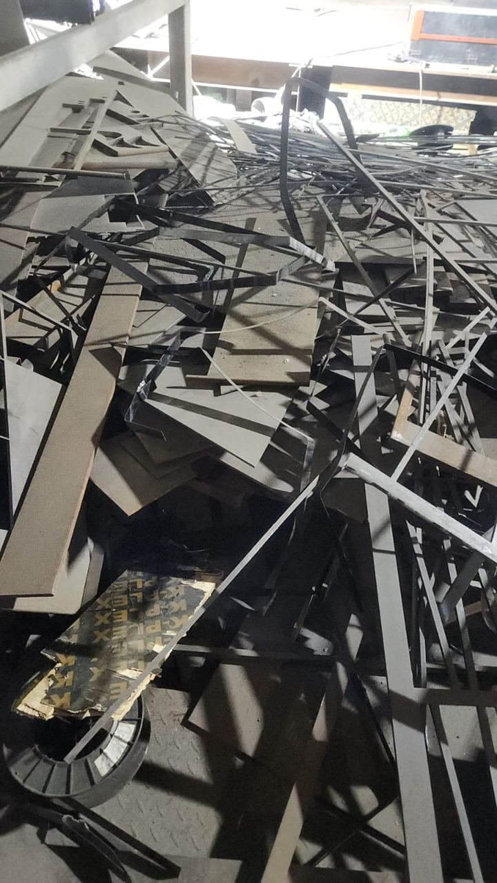 Heap of dark steel offcuts and cut plate inside a factory building